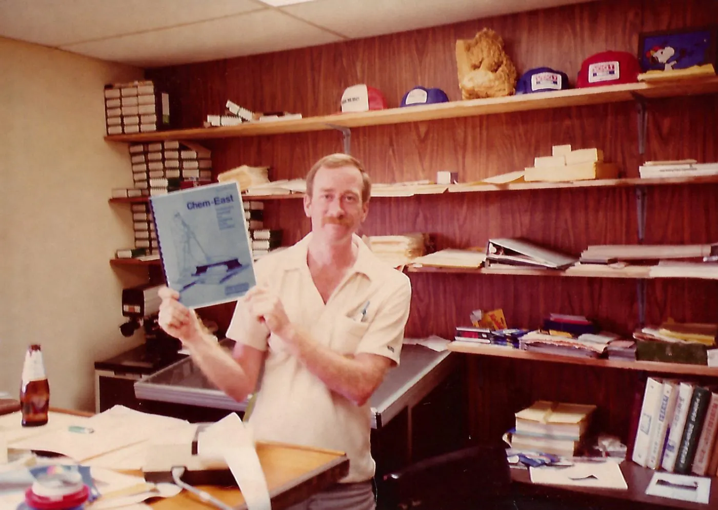 A SESCO founder at his desk, holding up an equipment catalog